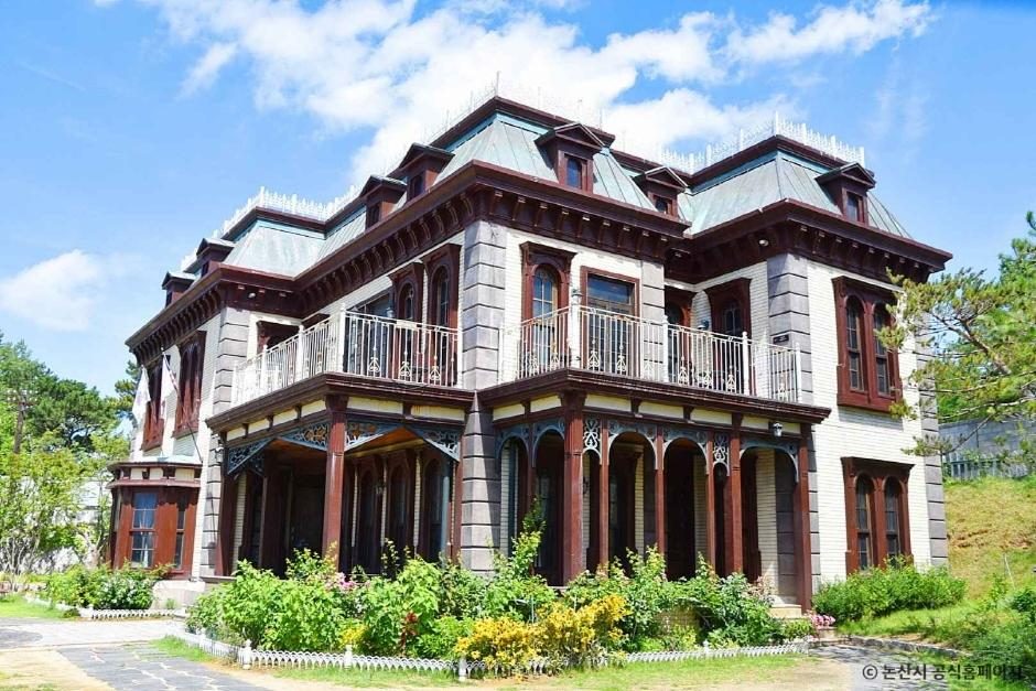 Glory Hotel, the Western-style mansion at Sunshine Land in Nonsan, with verandas and decorative woodwork under a blue sky