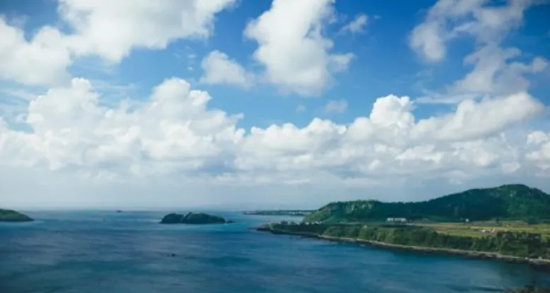 Bright clouds over the turquoise Jeju west coast with green headlands and small islets